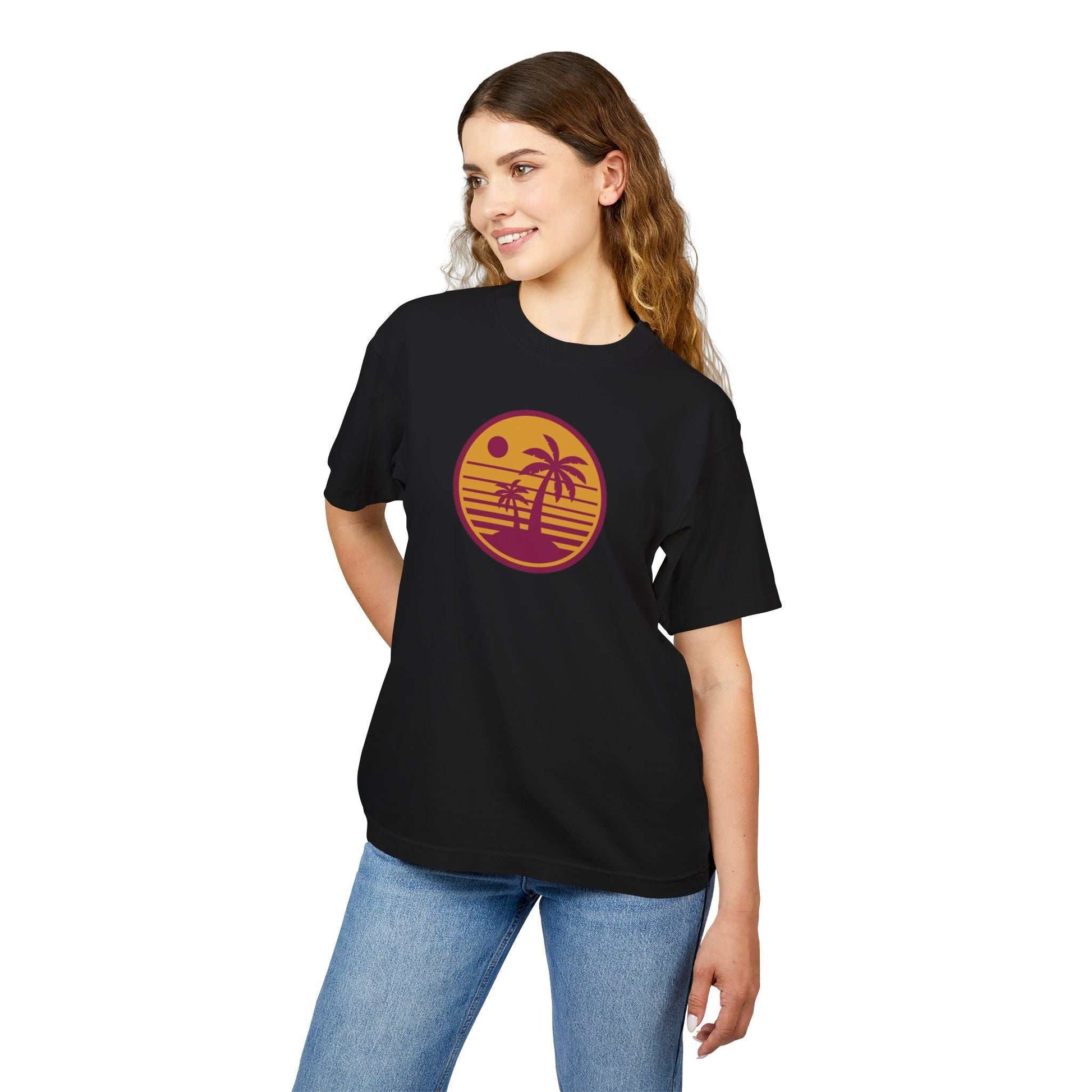 Unisex Urban Heavy Tee with retro sunset palm tree design, black color, worn by a woman.